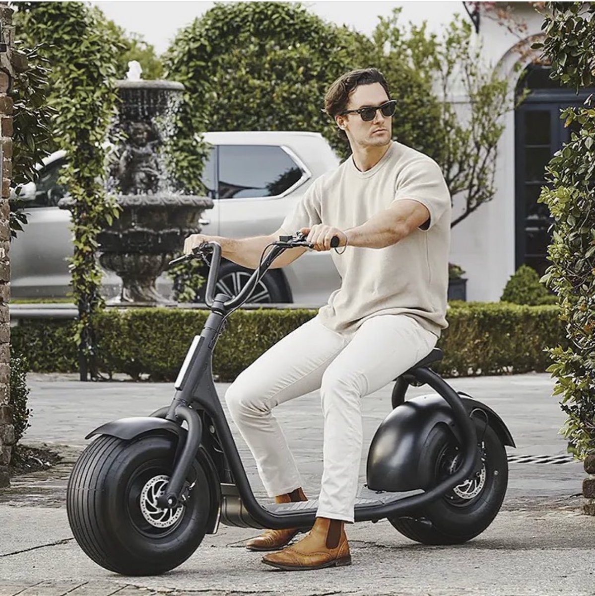 Rider on a Kaaspeed fat-tire electric scooter in a courtyard